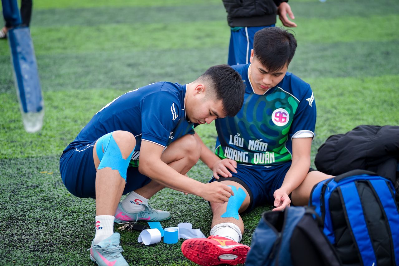 Home Football players applying kinesiology tape on the field in Hà Nội, Vietnam.