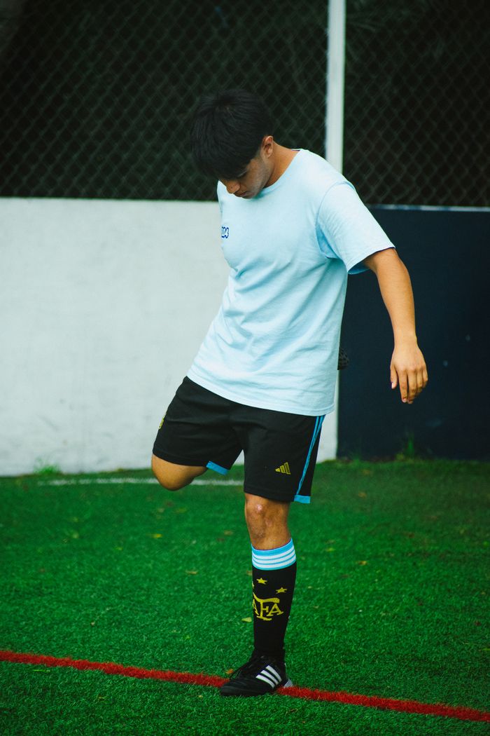 Services A young footballer practicing skills on a lush green field in Mexico City, wearing athletic attire.