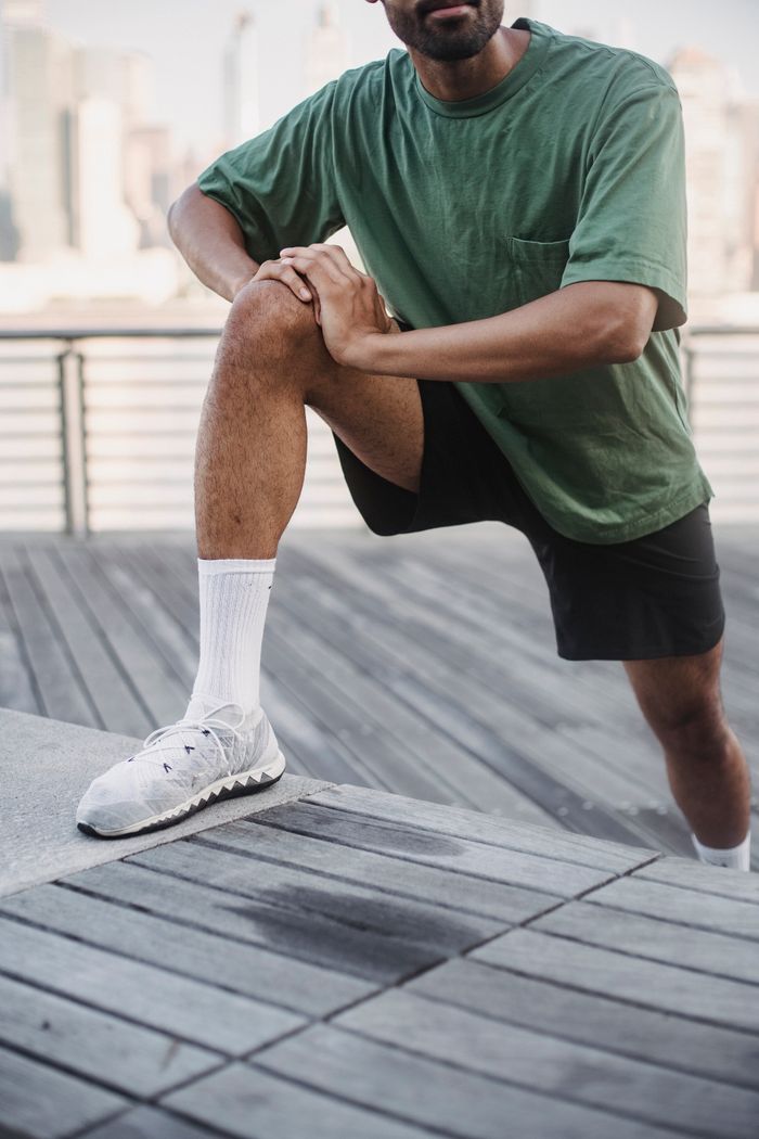 The Art of Drawing Readers In: Your attractive post title goes here Adult man in green t-shirt stretching on a wooden deck outdoors, preparing for exercise.