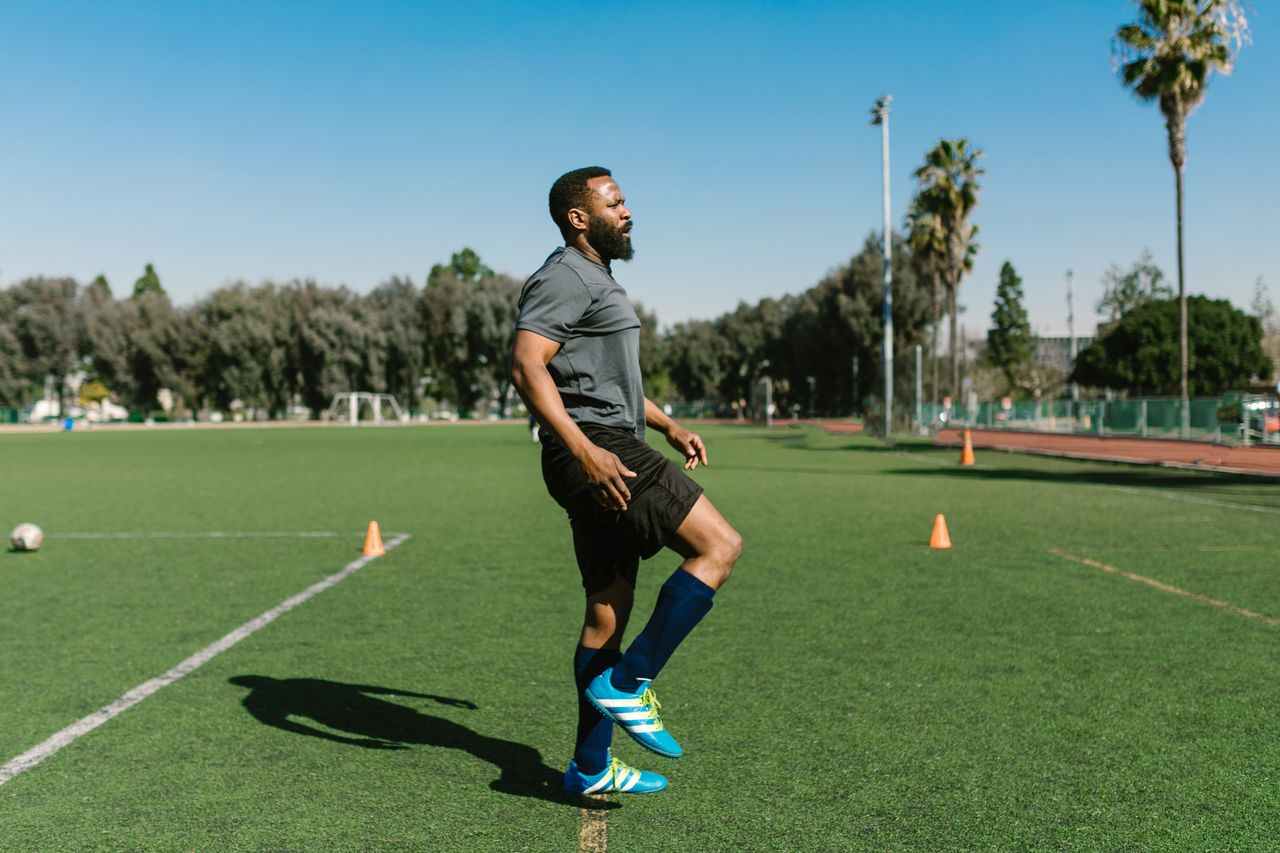Mastering the First Impression: Your intriguing post title goes here A soccer player warming up with exercises on a sunny day at an outdoor field.